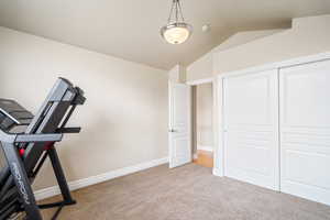 Exercise room featuring lofted ceiling, carpet, and baseboards