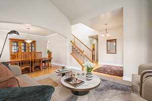 Living area featuring stairs, light wood finished floors, arched walkways, and baseboards