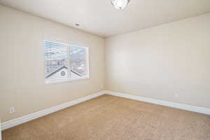 Spare room featuring carpet floors, baseboards, and visible vents