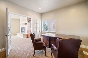 Home office featuring carpet, a fireplace, visible vents, and baseboards