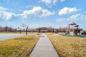 View of basketball court with a yard, playground community, a gazebo, community basketball court, and fence