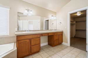 Bathroom featuring double vanity, a walk in closet, a sink, and tile patterned floors