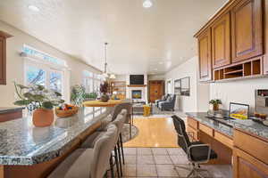 Kitchen with recessed lighting, brown cabinets, decorative light fixtures, and a kitchen breakfast bar