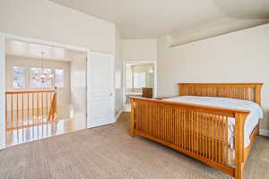 Bedroom with an inviting chandelier, multiple windows, vaulted ceiling, and carpet flooring