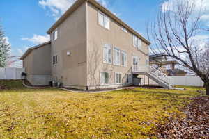 Rear view of house featuring stairway, fence, a yard, central air condition unit, and stucco siding