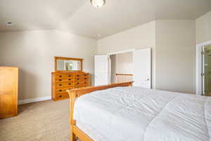 Bedroom featuring light carpet, vaulted ceiling, visible vents, and baseboards