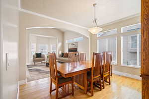 Dining area featuring light wood-style flooring, arched walkways, baseboards, and ornamental molding