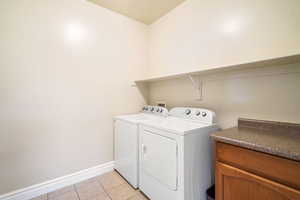 Laundry area with laundry area, light tile patterned flooring, baseboards, and separate washer and dryer