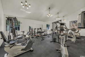 Workout area featuring a chandelier, vaulted ceiling, and a textured ceiling