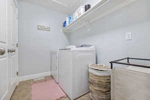 Laundry area featuring visible vents, light tile patterned flooring, laundry area, independent washer and dryer, and baseboards