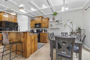 Kitchen featuring an island with sink, a breakfast bar, decorative light fixtures, black appliances, and backsplash