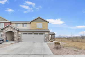 View of front of house with concrete driveway, stone siding, an attached garage, a mountain view, and stucco siding