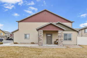 View of front facade featuring stone siding, fence, stucco siding, and a front yard