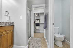 Full bath featuring toilet, a stall shower, vanity, baseboards, and tile patterned floors