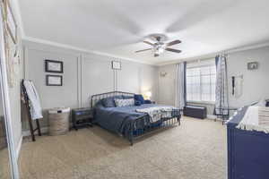 Bedroom with a textured ceiling, carpet floors, ornamental molding, and a decorative wall