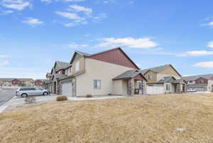 View of front of property with concrete driveway, a front lawn, stone siding, and a residential view