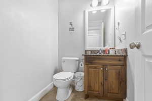 Half bathroom featuring tile patterned flooring, baseboards, vanity, and toilet