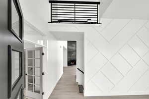 Hallway with a high ceiling, light wood-type flooring, and baseboards