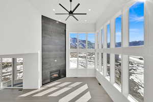 Unfurnished sunroom with a large fireplace, visible vents, a mountain view, and a ceiling fan