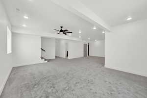 Interior space featuring light colored carpet, recessed lighting, a ceiling fan, visible vents, and stairs