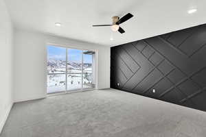 Spare room featuring baseboards, carpet floors, a mountain view, and a ceiling fan