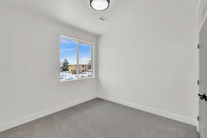 Empty room featuring carpet flooring, visible vents, and baseboards