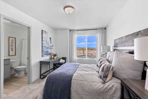 Bedroom with light carpet, connected bathroom, and a textured ceiling