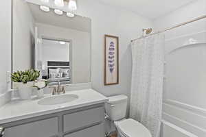 Ensuite bathroom featuring toilet, shower / bath combination with curtain, connected bathroom, and vanity