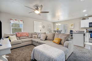 Living room with a textured ceiling, ceiling fan with notable chandelier, dark wood finished floors, and recessed lighting