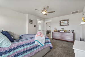 Bedroom with ceiling fan, visible vents, dark colored carpet, and a textured ceiling