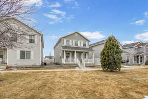 View of front facade with a porch, a front yard, and central AC