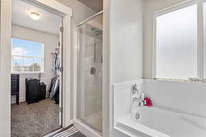 Full bath featuring a garden tub, a shower stall, and a walk in closet