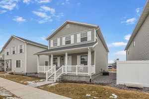 View of front of house featuring a porch, a front yard, central AC, and board and batten siding