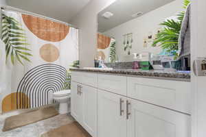 Bathroom featuring a textured ceiling, toilet, vanity, and visible vents