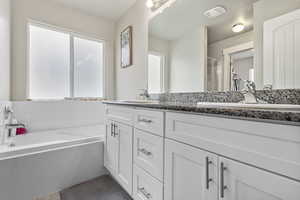 Bathroom featuring visible vents, a sink, a garden tub, and double vanity