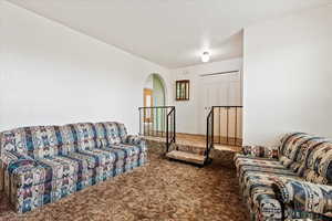 Living room with carpet floors, arched walkways, and a textured ceiling