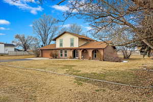 View of front of property featuring an attached garage, brick siding, fence, driveway, and a front yard