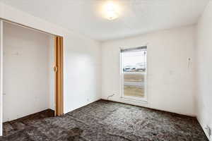 Unfurnished bedroom featuring dark carpet and a closet