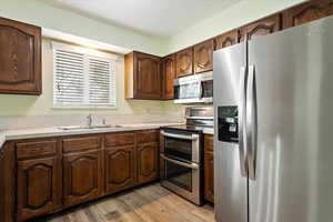 Kitchen featuring stainless steel appliances, light wood-type flooring, a sink, and light countertops