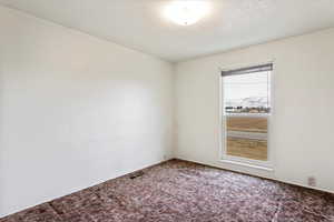 Carpeted empty room featuring visible vents and a textured ceiling