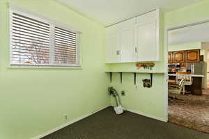 Washroom with cabinet space, dark carpet, hookup for an electric dryer, and baseboards