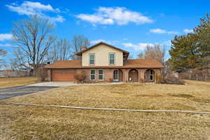 Traditional home with a garage, a front yard, concrete driveway, and brick siding