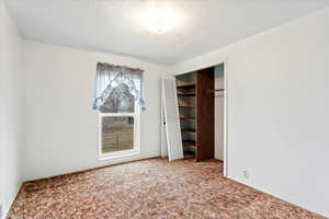 Unfurnished bedroom with a textured ceiling, a closet, and carpet