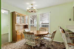 Dining room featuring light colored carpet, a notable chandelier, visible vents, and baseboards