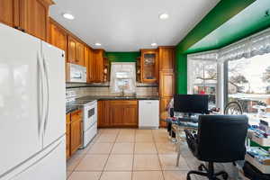 Kitchen featuring sink, white appliances, tasteful backsplash, and light tile patterned floors