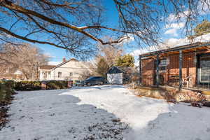 Yard layered in snow with a garage and an outdoor structure