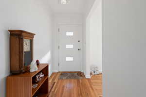 Entryway with a notable chandelier, hardwood / wood-style flooring, and ornamental molding