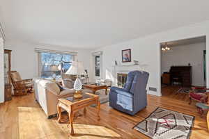 Living room featuring light wood-type flooring, ornamental molding, and a notable chandelier