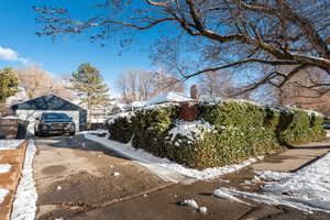 View of snowy exterior featuring a garage and an outdoor structure