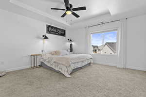 Bedroom with carpet floors, a tray ceiling, visible vents, ceiling fan, and baseboards